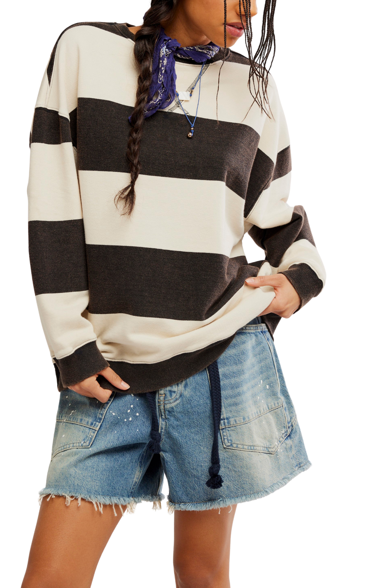 Person wearing a black and white striped sweater with denim shorts on a plain background