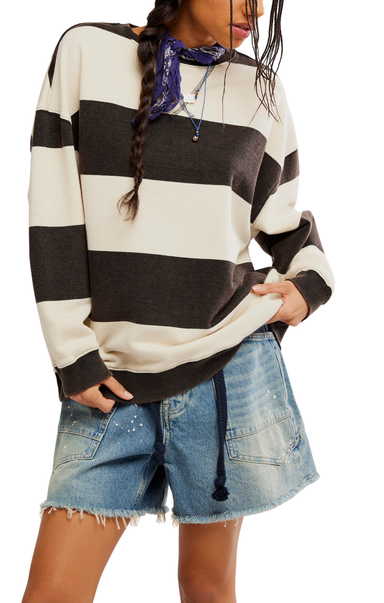 Person wearing a black and white striped sweater with denim shorts on a plain background