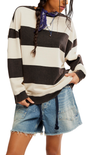Person wearing a black and white striped sweater with denim shorts on a plain background