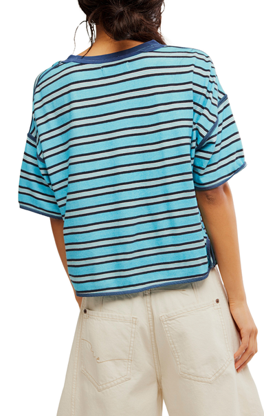 Person wearing a blue and white striped shirt with beige pants on a plain background