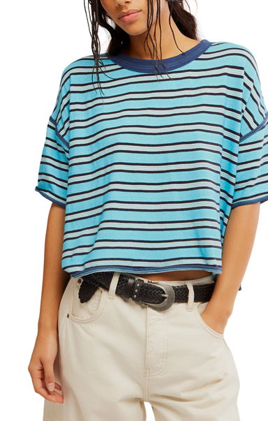 Person wearing a blue and white striped t-shirt with beige pants on a plain background