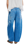 Blue denim pants with white floral patterns worn by a person on a white background