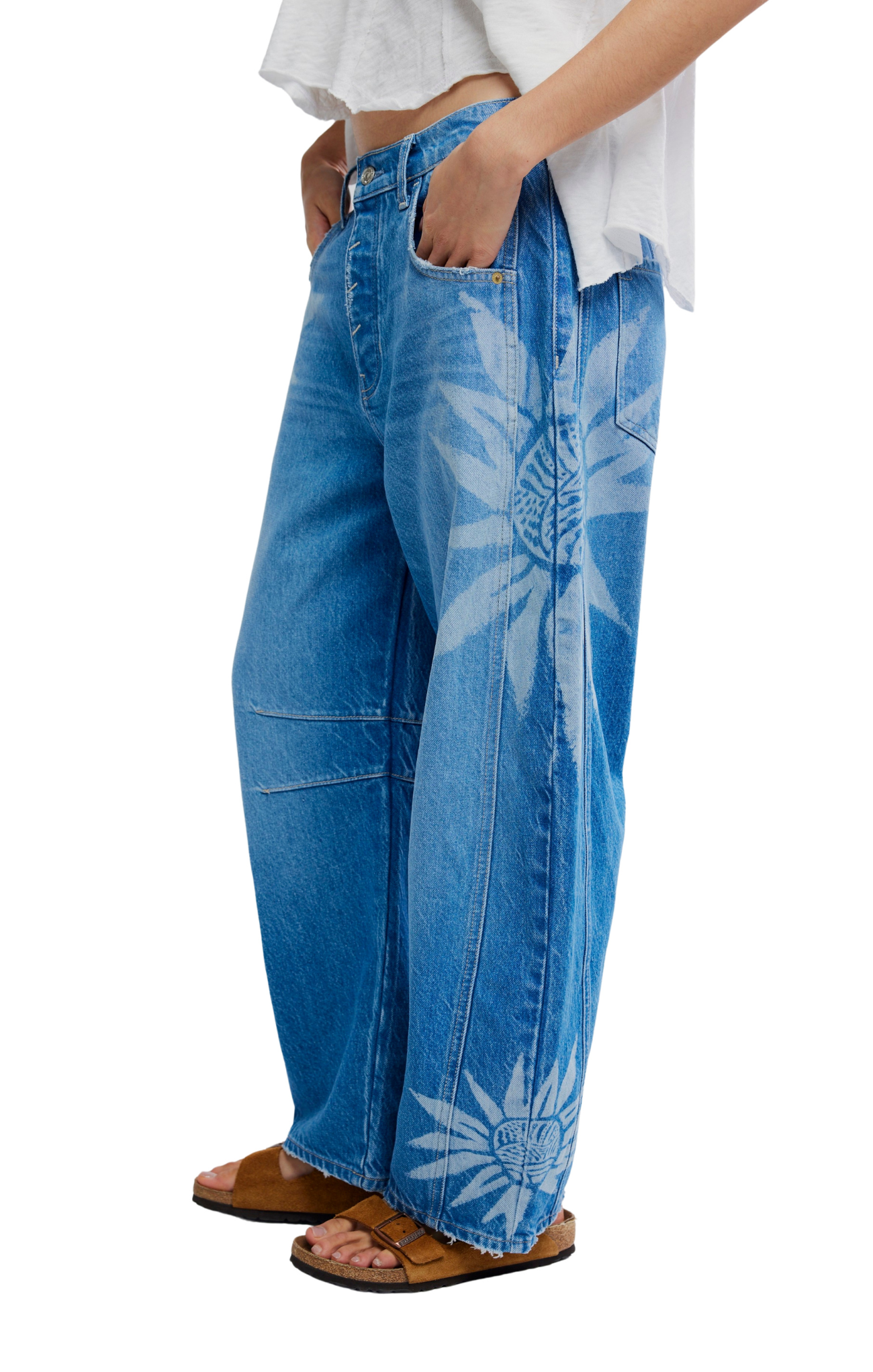 Blue jeans with floral patterns worn by a person on a white background