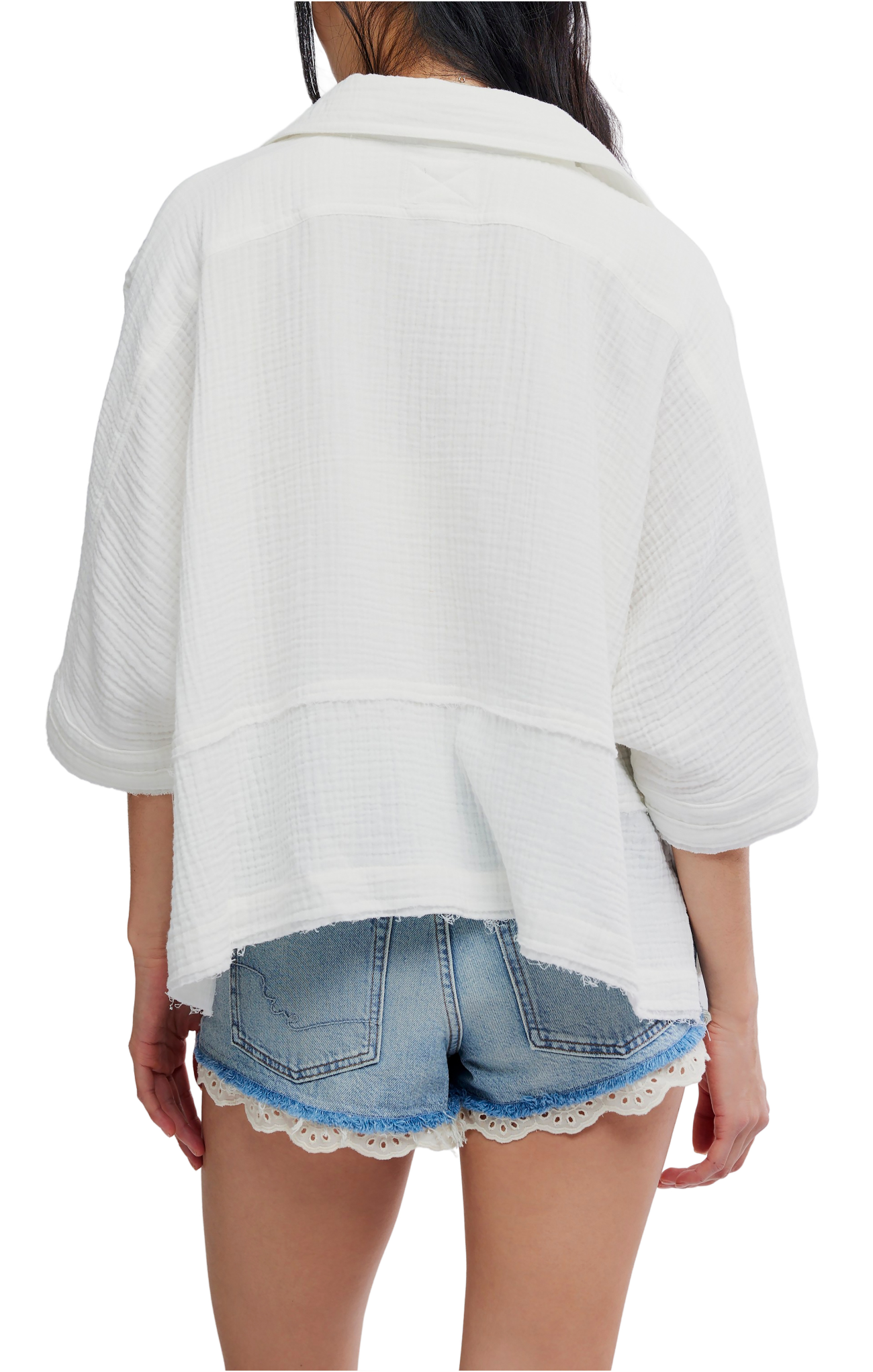 Person wearing a white oversized shirt and denim shorts with lace trim on a white background