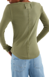 Person wearing a green long-sleeve shirt and blue jeans on a white background