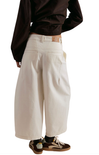 Person wearing beige wide-leg pants with a plain background