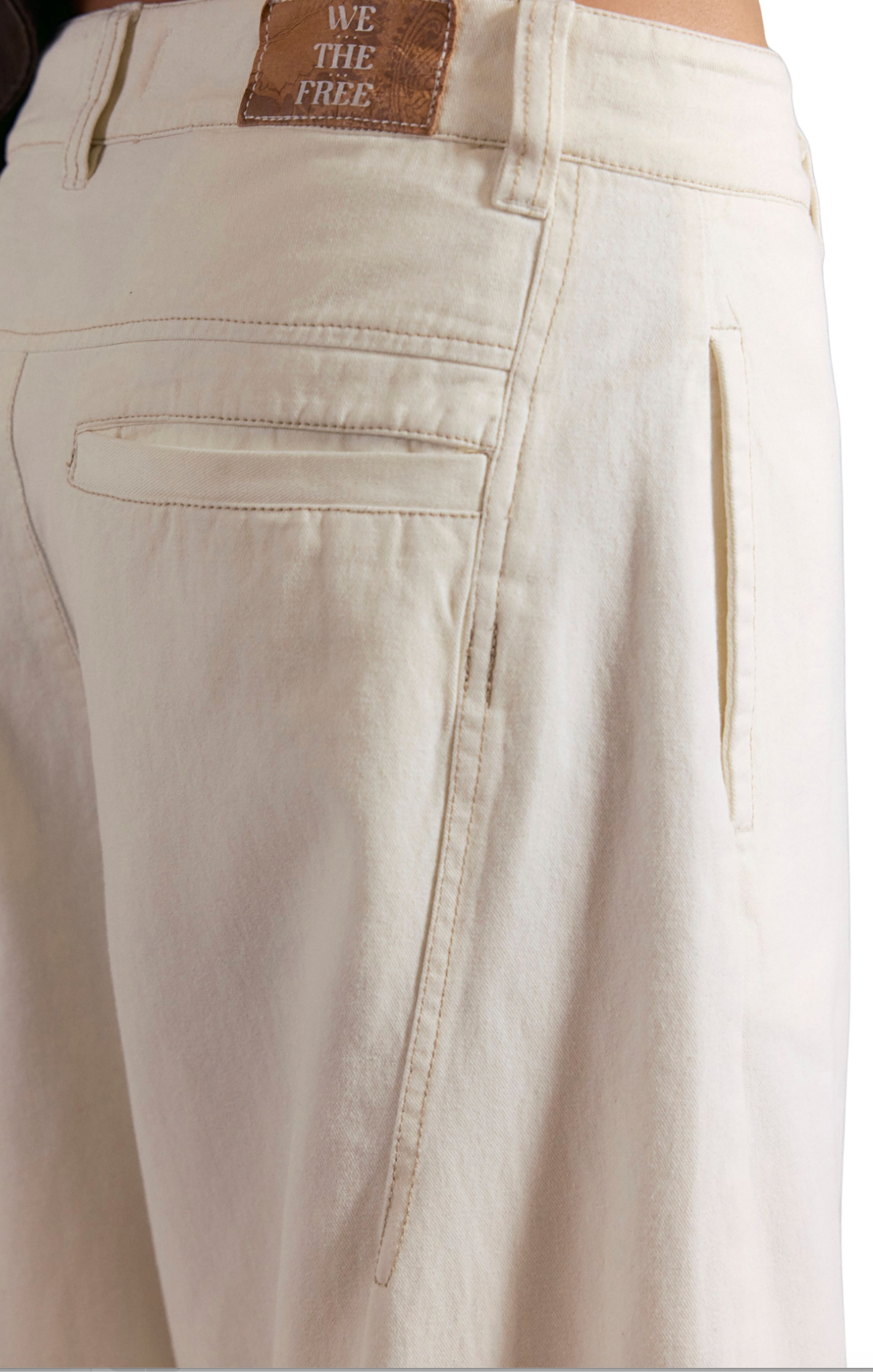 Close-up of beige pants with a brand label on the waistband.