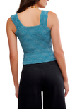 Woman wearing a blue lace top and black pants on a white background