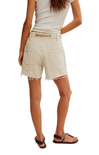 Beige shorts worn by a person on a white background