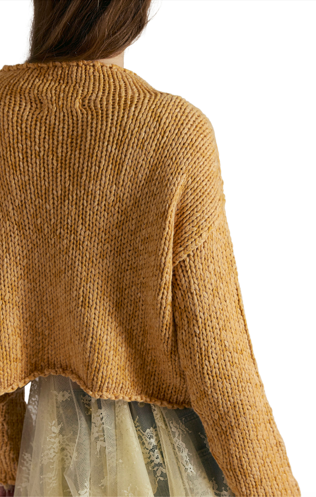 Close-up of a person wearing a mustard yellow knitted sweater on a white background