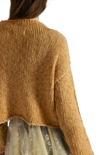 Close-up of a person wearing a mustard yellow knitted sweater on a white background