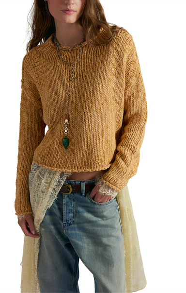 Person wearing a mustard yellow knitted sweater with a white background