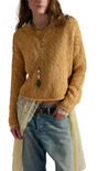 Person wearing a mustard yellow knitted sweater with a white background