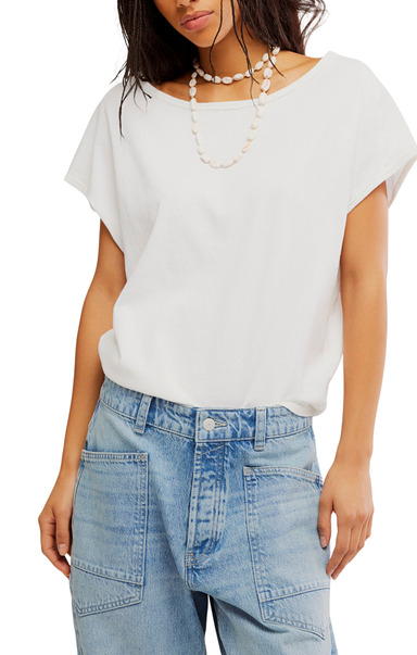 Woman wearing a white top and light blue jeans with a plain background