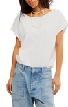 Woman wearing a white top and light blue jeans with a plain background