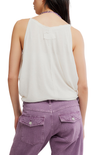 Person wearing a white sleeveless top and purple pants on a white background