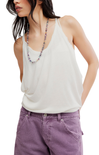 Woman wearing a white tank top and purple pants with a beaded necklace on a white background