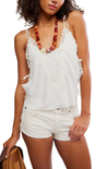 Woman wearing a white lace top and shorts with a necklace, holding a brown bag.