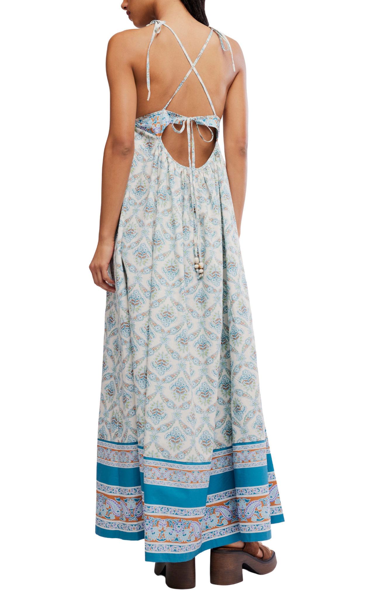 Woman wearing a patterned dress with open back on a white background
