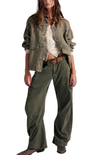 Person wearing a green jacket and wide-leg pants on a white background