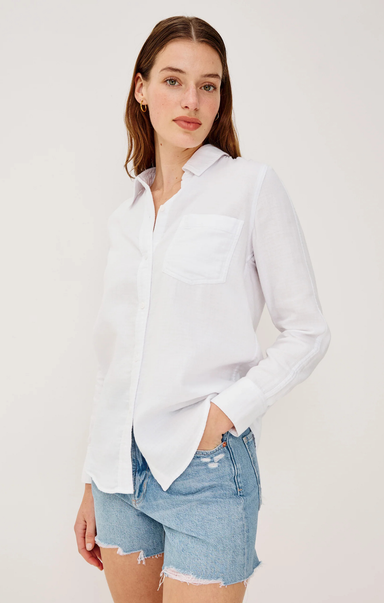 Woman wearing a white shirt and denim shorts on a plain background