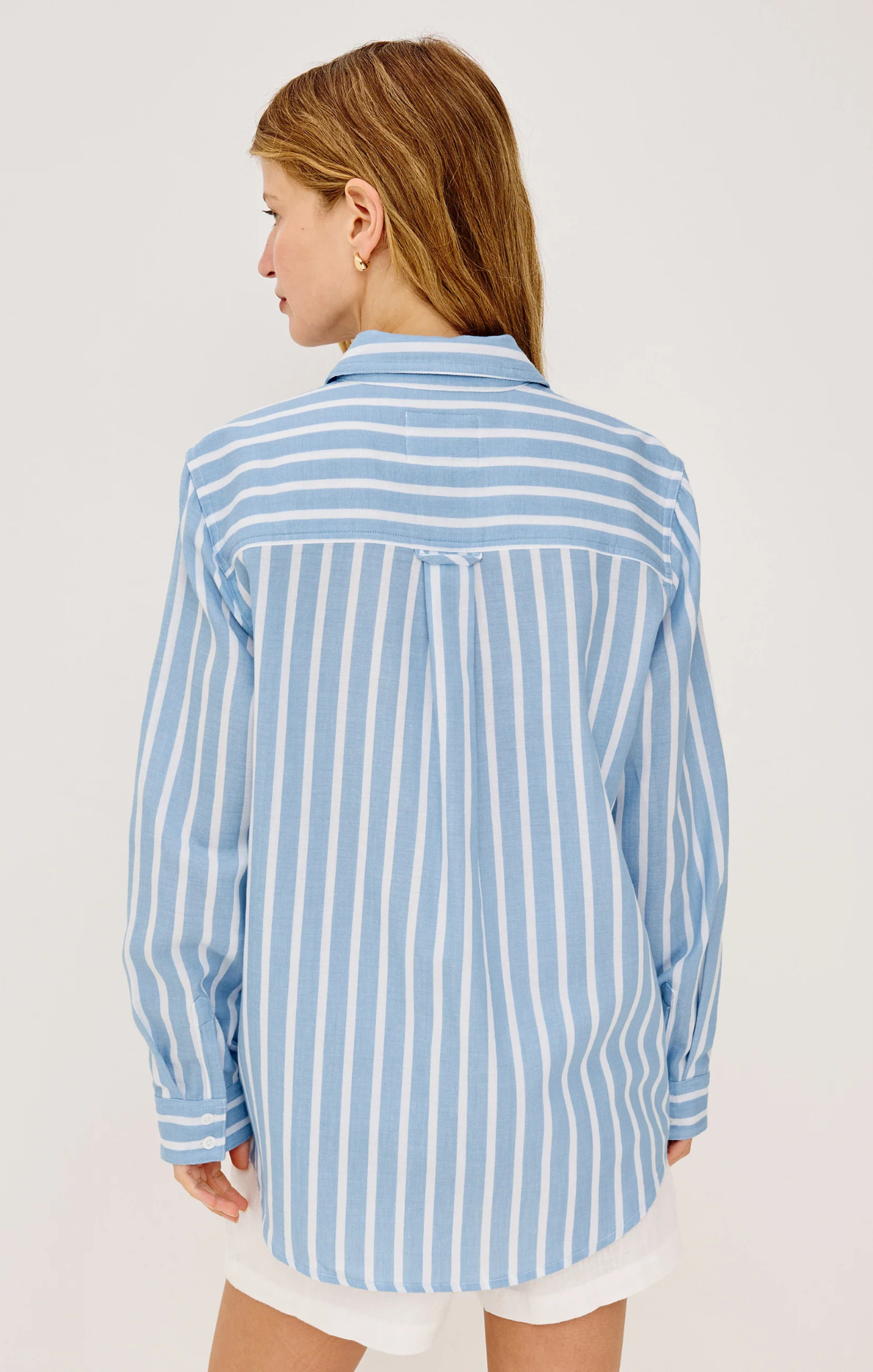 Woman wearing a blue and white striped shirt on a plain background