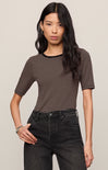 Woman wearing a striped shirt and black pants against a plain background