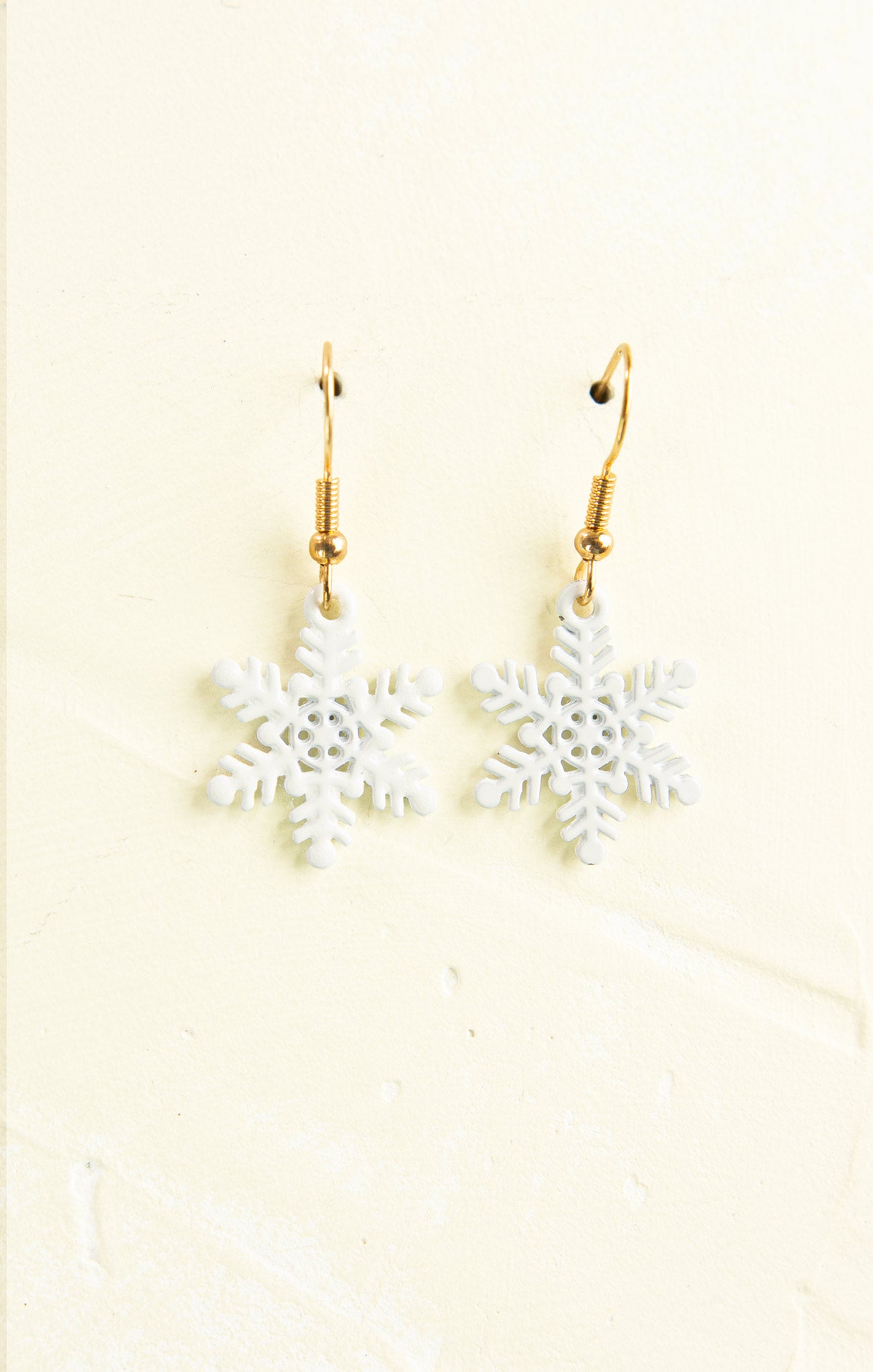 Snowflake earrings on a beige background