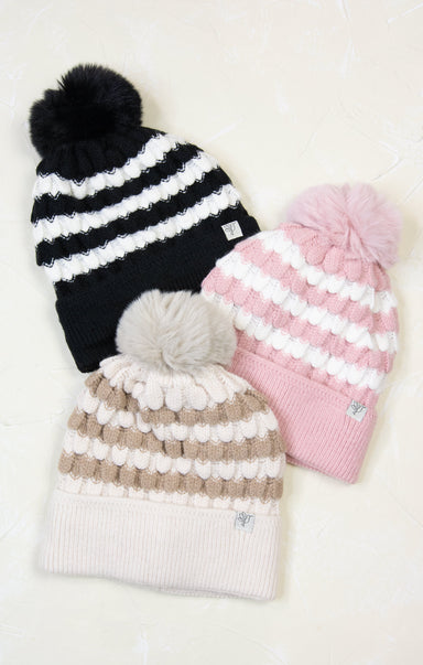 Three knit hats with pom-poms in black, pink, and beige on a white background