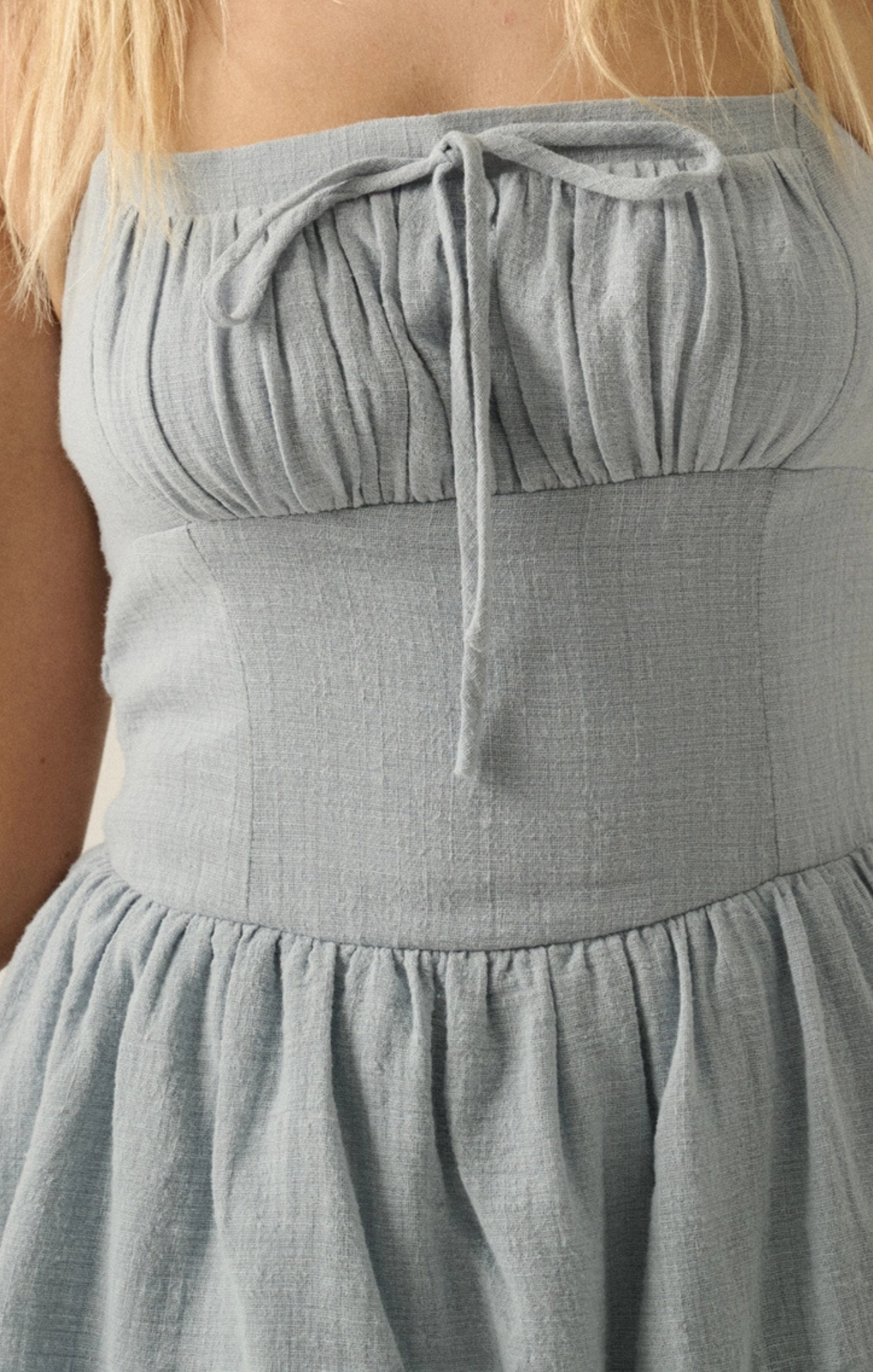 Gray strapless dress with a tie detail on a blurred background