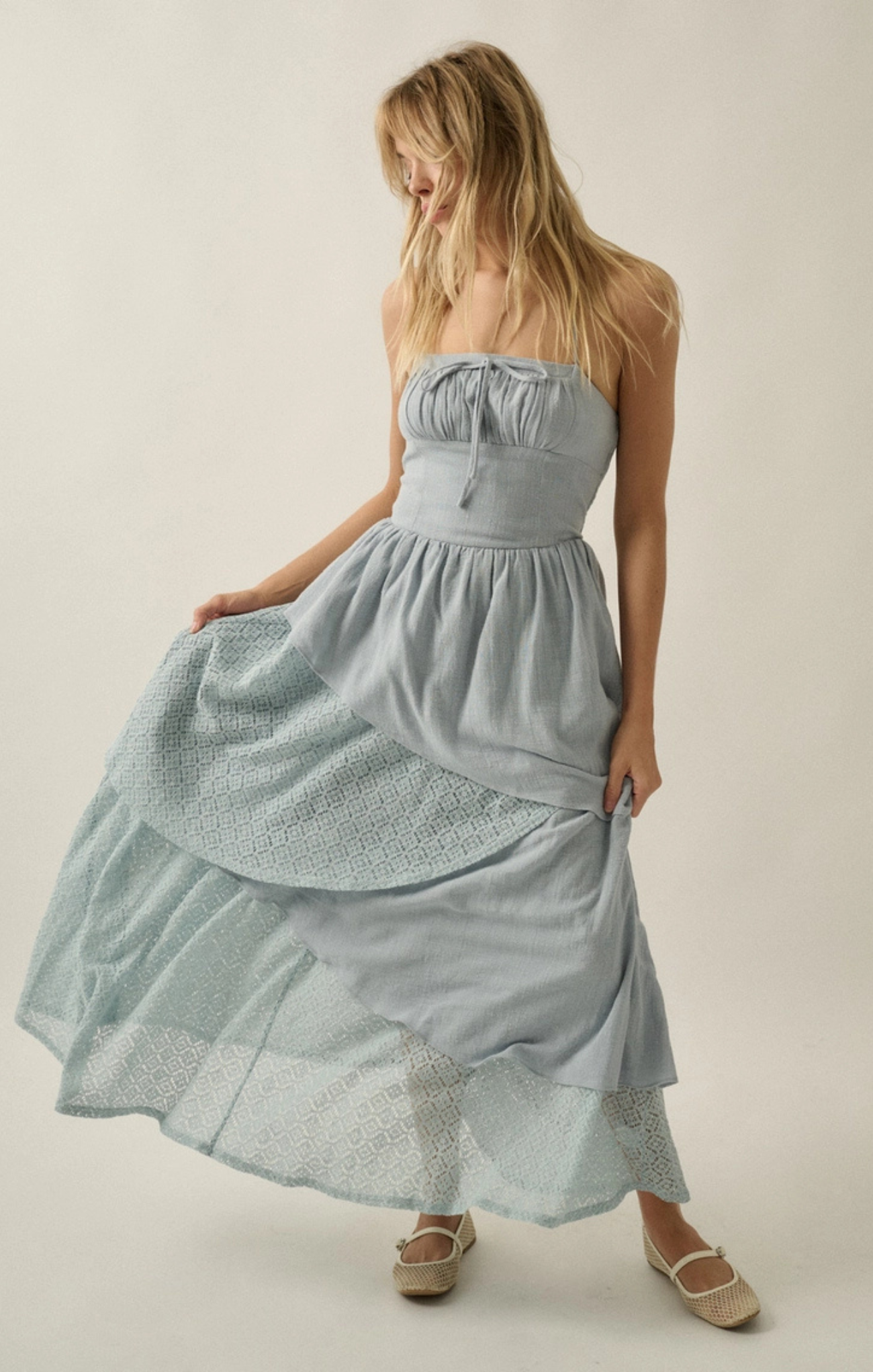 Woman wearing a light blue strapless dress with a textured pattern on a plain background