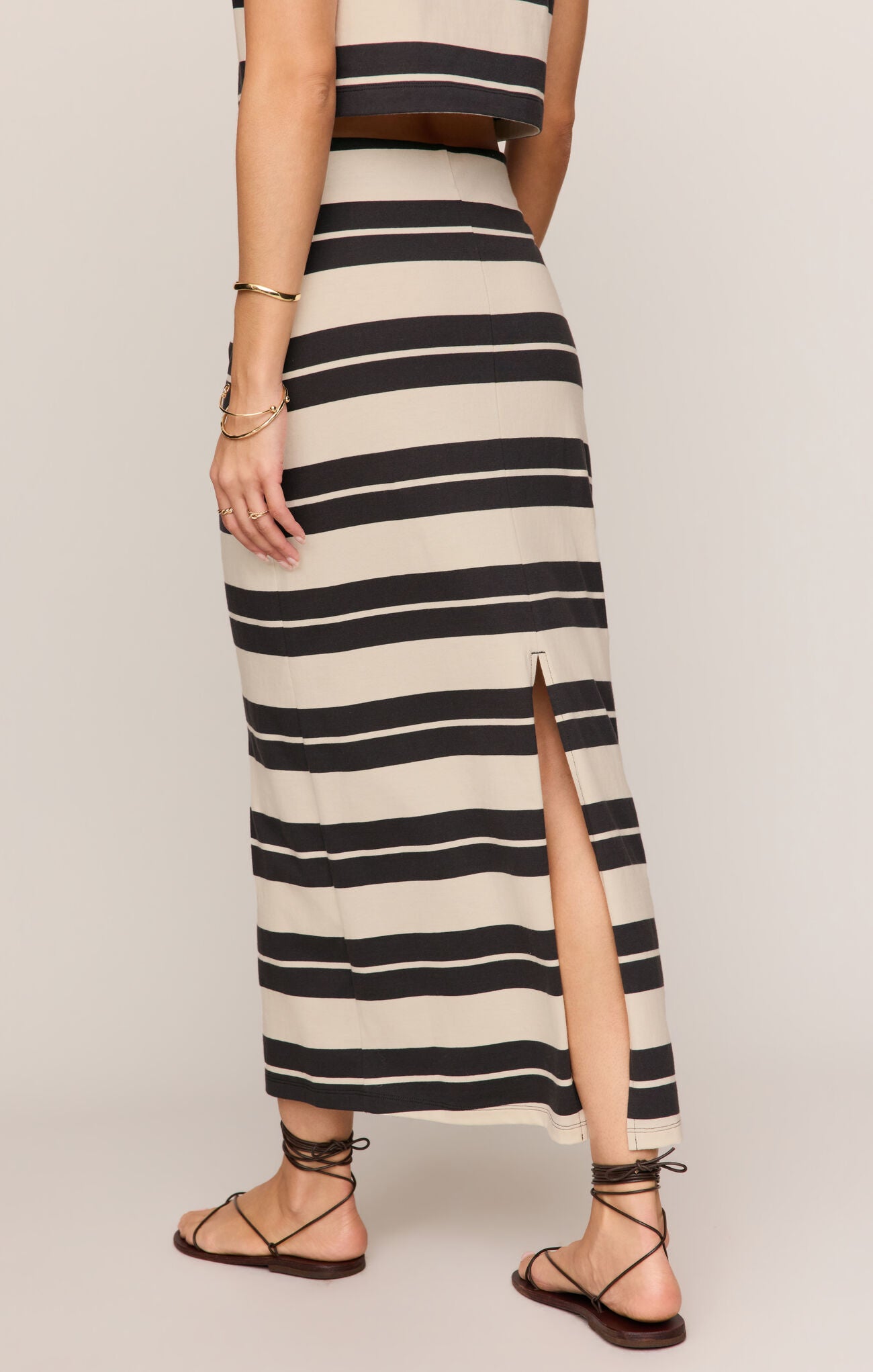 Person wearing a black and white striped dress with a slit on a plain background