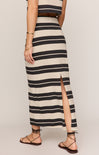 Person wearing a black and white striped dress with a slit on a plain background