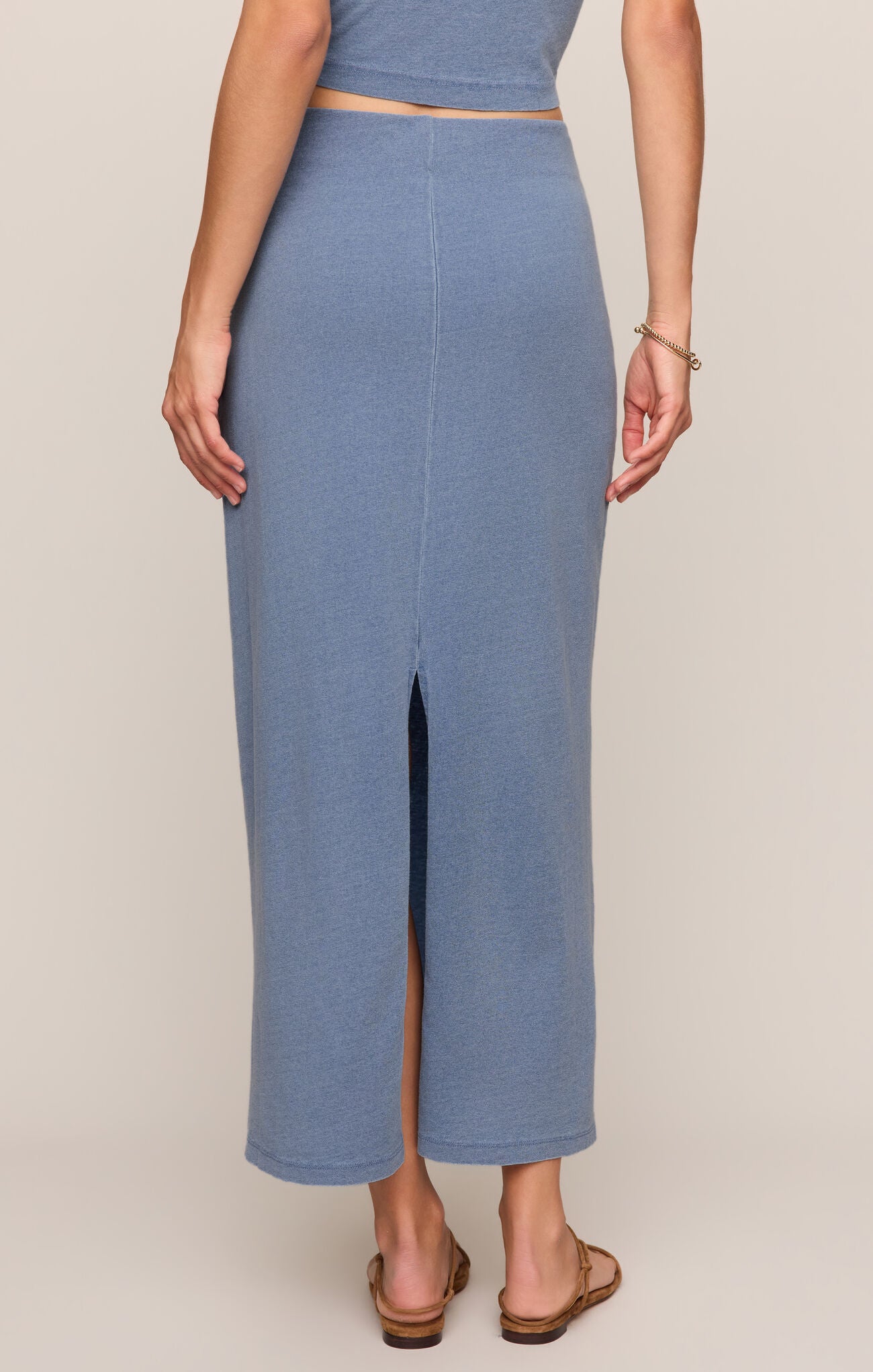 Person wearing a blue outfit with a slit skirt on a beige background