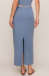 Person wearing a blue outfit with a slit skirt on a beige background