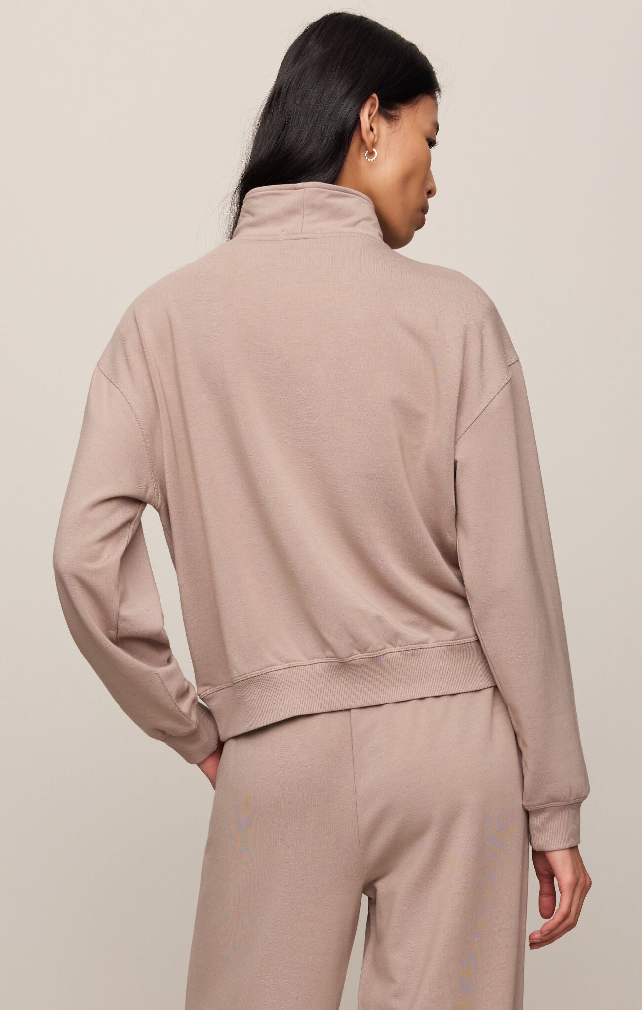 Person wearing a beige tracksuit against a plain background