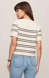 Woman wearing a striped shirt and jeans against a plain background