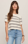 Woman wearing a striped shirt and jeans against a plain background