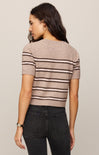 Woman wearing a striped sweater and dark jeans on a plain background