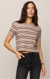 Woman wearing a striped sweater and black jeans against a plain background