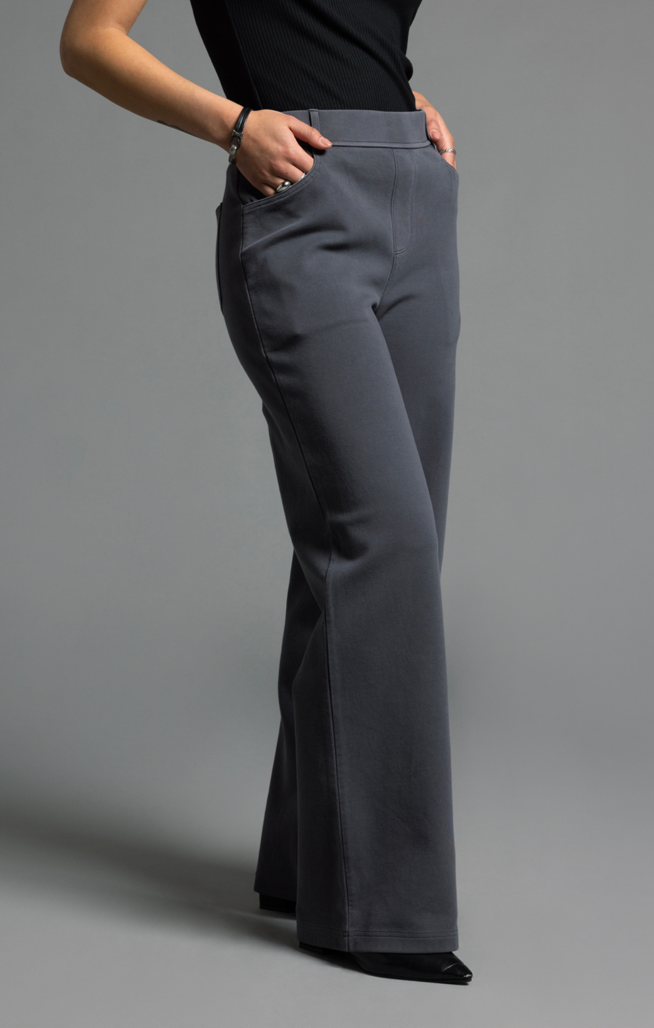 Gray flared pants worn by a person on a gray background