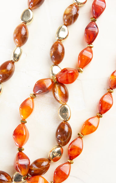 Necklace with orange and gold beads on a white background