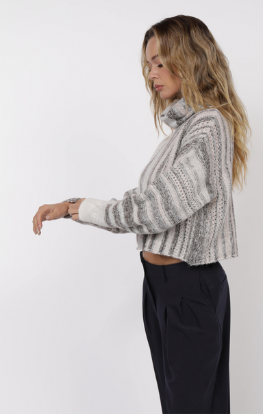 Woman wearing a gray and white patterned sweater against a white background