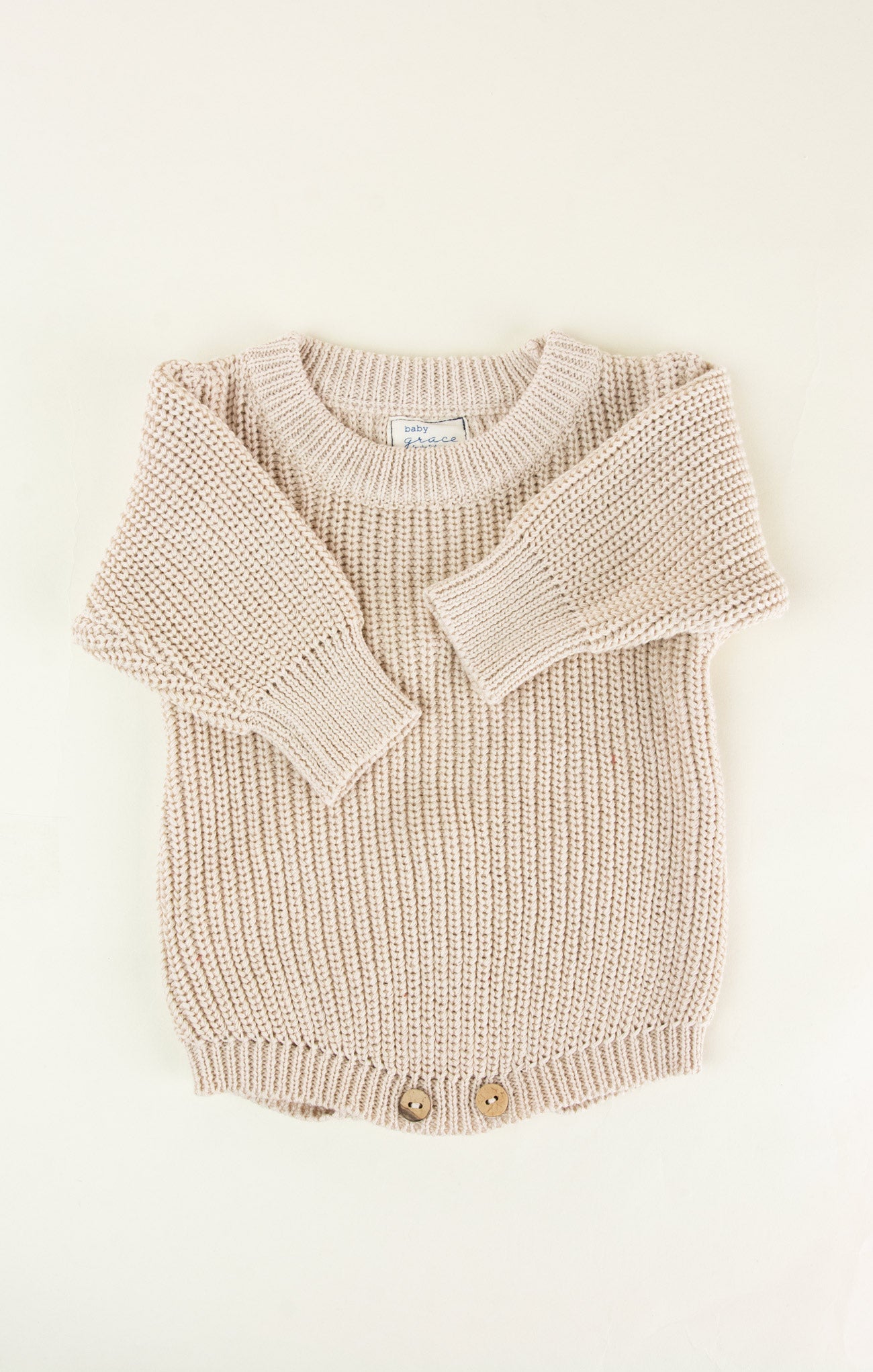 Knitted beige baby romper on a white background