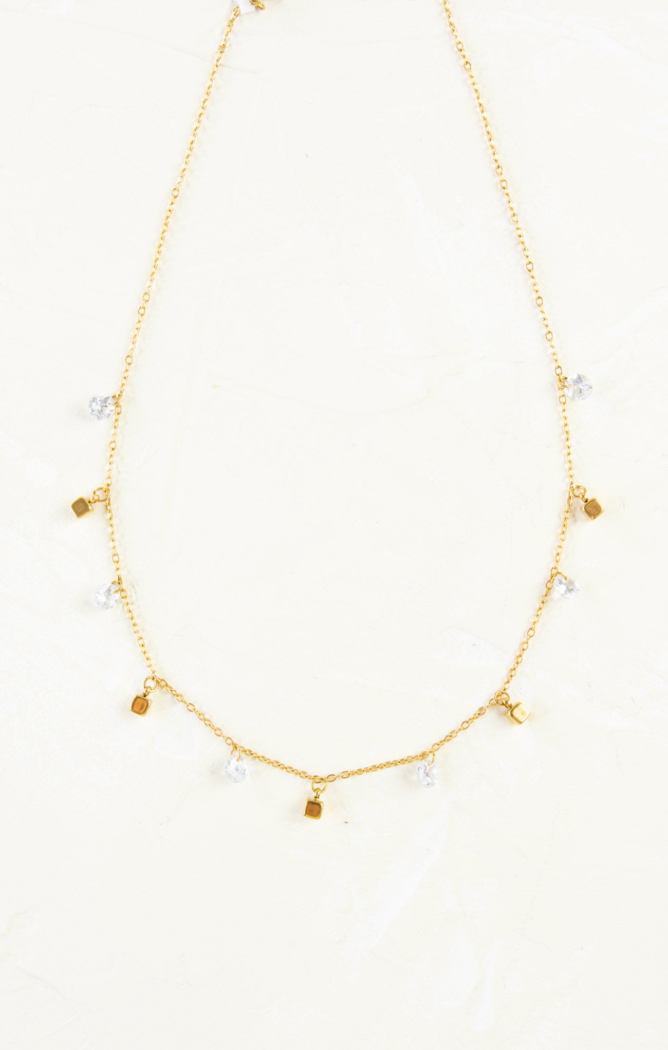 Gold necklace with small pendants on a white background