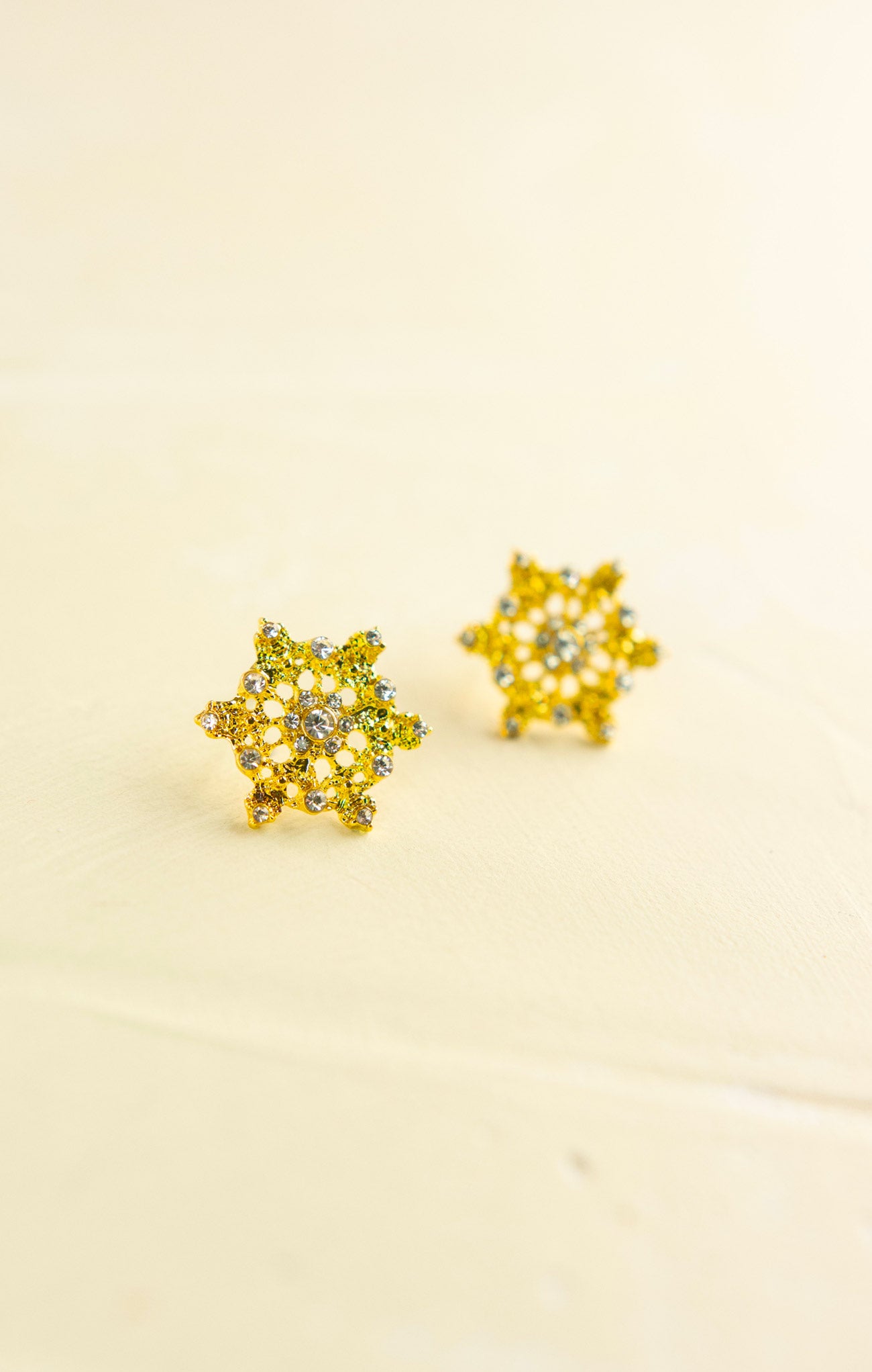 Pair of yellow flower-shaped earrings on a beige background
