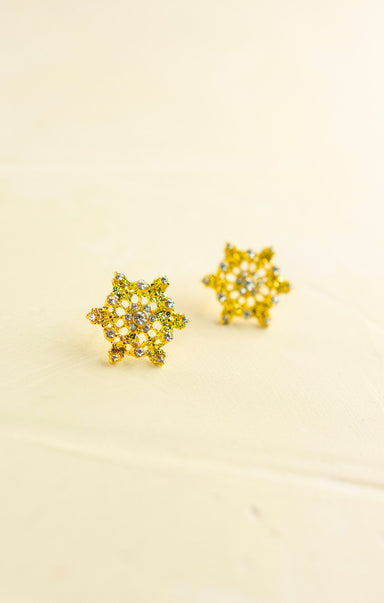 Pair of yellow flower-shaped earrings on a beige background