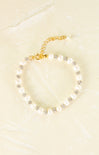 Pearl bracelet with gold chain on a beige background