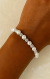 Pearl bracelet with crystals on a wrist against a neutral background