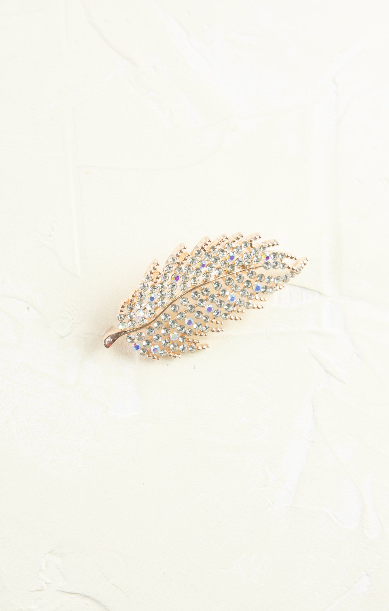 Decorative feather brooch with gemstones on a light background